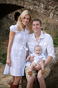 Jennifer and Chris Bridgman with infant son sitting on Chris's lap.